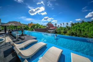 芭东海滩普吉岛-安达曼海滩海景度假酒店 Phuket-Andaman Beach Seaview Hotel的一个带椅子的游泳池,水中有人