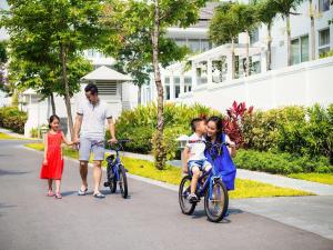 岘港Premier Village Danang Resort Managed By Accor的一名男子和两名儿童骑着自行车在街上