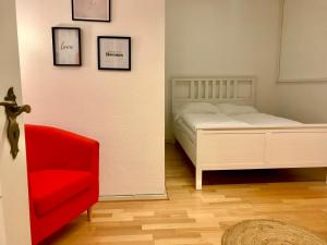 亚琛Relax Aachener Boardinghouse Budget的一间卧室配有一张床和一张红色椅子