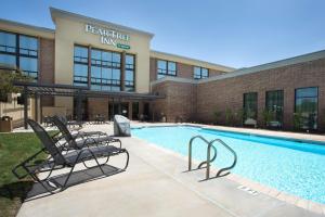 圣安东尼奥圣安东尼奥机场梨树酒店的一座带两把椅子的游泳池位于大楼旁