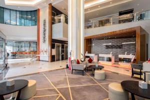 迪拜Ramada by Wyndham Dubai Barsha Heights的大楼内带桌椅的大堂