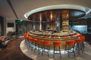 迪拜Ramada by Wyndham Dubai Barsha Heights的一间大酒吧,在房间内摆放着橙色椅子