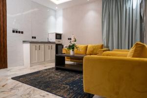 吉达لحظات الفندقية حراء Lahdat Serviced Apartments的一间带黄色家具的客厅和一间厨房