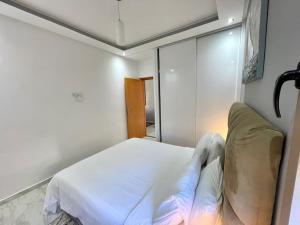 特马拉A2 Appartement entièrement neuf au cœur de Témara的卧室配有白色的床和镜子
