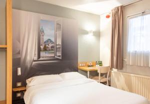 里摩日B&B HOTEL Limoges 2的一间卧室配有一张床、一张书桌和一个窗户。