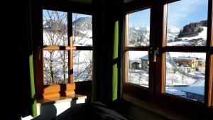 EmbachApartments Embach的一间设有三扇窗户的客房,俯瞰着雪山