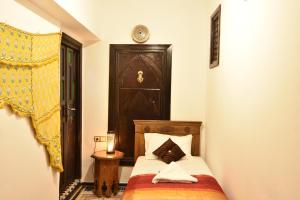 非斯Dar Aya Fes的一间小卧室,配有一张带木制床头板的床
