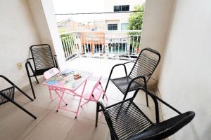 邦热苏斯-达拉帕Excelente apto com churrasq Bom Jesus da Lapa BA的阳台配有粉红色的桌椅和窗户。