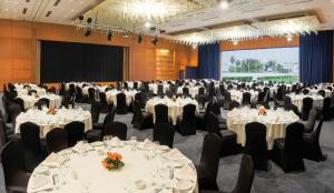 斯希拉特安菲特里特宫度假酒店及Spa的宴会厅配有桌椅和屏幕