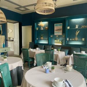 波尔尼谢Hotel de Charme Le Sud Bretagne的餐厅设有白色的桌椅和蓝色的墙壁