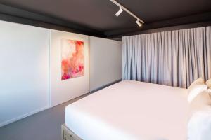 布鲁塞尔nhow Brussels Bloom的卧室配有白色的床和绘画作品