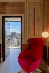 马泰拉Quarry Resort的窗户房间里一张红色的椅子