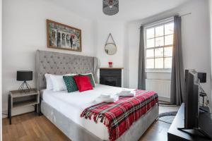 伦敦Gorgeous One Bed in the Heart of Central London的卧室配有白色大床和红色及绿色枕头