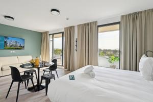 科隆布All Suites Paris Ouest Colombes的酒店客房带一张床、一张桌子和椅子