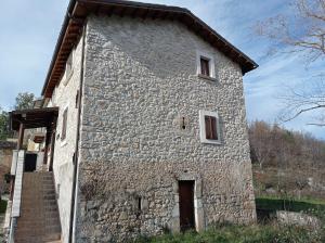 卡拉马尼科泰尔梅Famiglia nel vento的一座带两扇窗户和楼梯的大型石头建筑