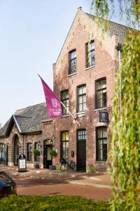 维格尔The Yard hotel Noordkade的一座大型砖砌建筑,上面有粉红色的标志