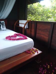 丹不拉Dambulla Tree House的一间卧室,床上有粉红色的鲜花