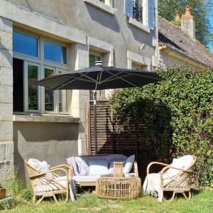 La MarcheChambre d'hôtes "Au bord de Loire"的院子里的桌椅和遮阳伞