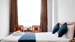 归仁La Cactus Hotel 1的一间卧室配有一张带蓝色枕头的床和一扇窗户。