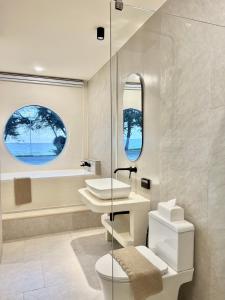 罗勇Sunvada Beach Rayong的一间带水槽和卫生间的浴室以及两个窗户。