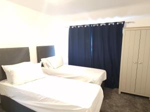 奥尔德伯里Walker Lodge的一间卧室配有两张床和蓝色窗帘