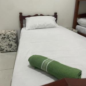 瓜鲁雅03 Doutor Hostel 800mts da praia的一张白色的床,上面有绿毛巾