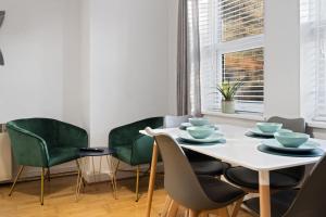 海维康Station Apartment High Wycombe的一间设有白色桌子和绿色椅子的用餐室