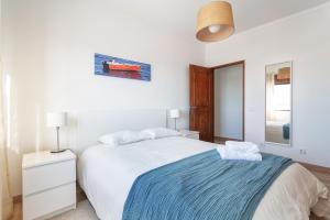 楼尔Spacious & Sunny Flat - Loulé的白色卧室配有一张带蓝色毯子的床