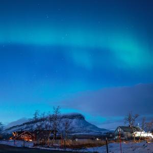 基尔匹斯扎我维Aurora View Lapland, Sky View Bedroom & Jacuzzi的雪覆盖的山,晚上有房子
