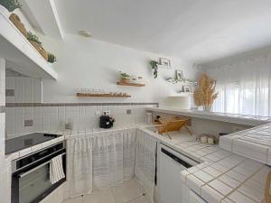 圣马迪拉莫Maison Saintes-Maries-de-la-Mer, 3 pièces, 4 personnes - FR-1-475-112的一间厨房,配有白色家电和白色瓷砖