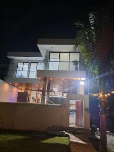 蒙塔尼塔Hermosa casa frentes al mar en Montanita con piscina的夜晚在房子前面有一棵棕榈树