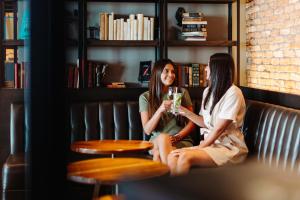 巴尔的摩巴尔的摩水岸万豪酒店的两个女人坐在长凳上喝葡萄酒