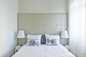 佩奇阿黛尔精品酒店的白色卧室配有一张带两盏灯的大床