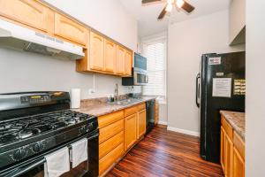 匹兹堡Pittsburgh's Sports Suite- FREE driveway Parking的厨房配有木制橱柜和黑色冰箱。