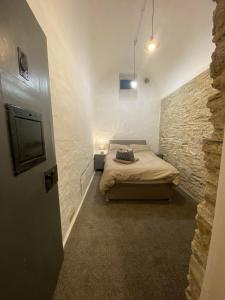 朗塞斯顿Victorian Police Station Apartment的一间卧室设有一张床和石墙
