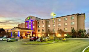 东叙拉古Holiday Inn Express & Suites Dewitt - Syracuse, an IHG Hotel的停车场内有车辆的旅馆