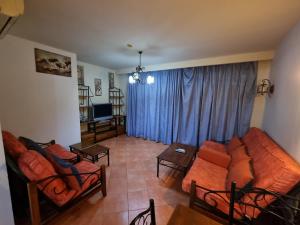艾因苏赫纳Porto sokhna Pyramids Apartments的带沙发和蓝色窗帘的客厅