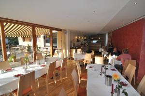 奥巴拉马高加尼奥托胡贝尔酒店的一间设有白色桌子的餐厅,有人坐在餐厅里