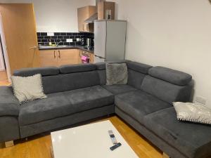 曼彻斯特Eaglet 2 Bedroom Luxury Home near Etihad Staduim的客厅设有一张灰色沙发,配有厨房