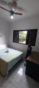 乌贝拉巴Casa próxima ao centro!的一间卧室配有一张带吊扇和窗户的床。
