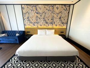 班吉Bangi Resort Hotel的卧室配有一张白色大床和一张蓝色沙发。