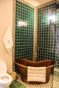 特基拉Hotel Boutique Gloriagave的浴室设有木制浴缸,位于绿色瓷砖淋浴间内