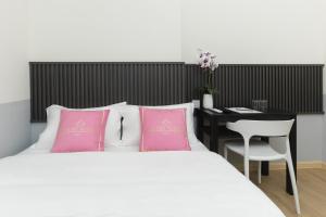 芙蓉Hotel Luma Senawang的一间卧室配有一张带粉色枕头的床和一张书桌