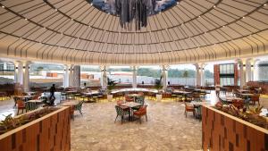 库宁岸Hotel Santika Premiere Linggarjati - Kuningan的一间带桌椅和大型天花板的餐厅