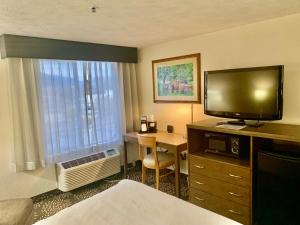 韦纳奇Wenatchee Inn的酒店客房配有一张床和一张书桌及一台电视