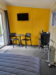 默奇森Murchison Motorhome Park的配有黄色墙壁、桌子和椅子的客房