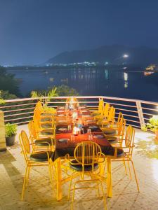 乌代浦Atrangi Hotel & lakeview cafe at PICHOLA LAKE by JD的一张长桌子,配有黄色椅子和一张桌子