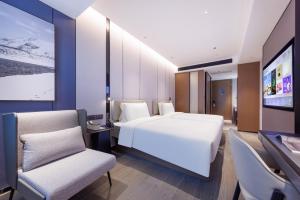 深圳深圳华强北商业中心亚朵酒店的卧室配有白色的床和2把椅子