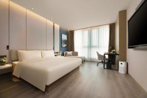 济南济南西站亚朵酒店的酒店客房设有一张白色大床和电视。