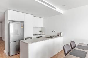 Barrack PointShellharbour Lakeview Apartment的厨房配有白色橱柜和不锈钢冰箱